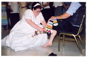 A bride putting the socks on the groom's unmarried older brother in preparation for his dance