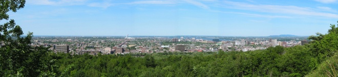 Panoramic view looking out over the east of Montreal, taken from Mont Royal. In the foreground the Mont-Royal Plateau. A bit further back, the Olympic Stadium with its 175-metre [574.1-foot] leaning tower. In the background, the Saint Lawrence River. July 2002. 