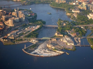 Le site des Chaudières : au centre, la grande chute ceinte du barrage en hémicycle, à gauche la rive gatinoise, à droite les îles, les anciens glissoirs à radeaux et la berge ottavienne, 2006